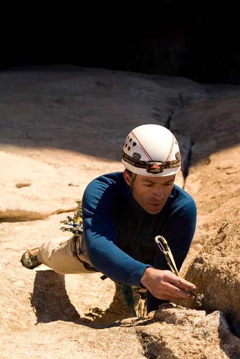 Kai Lin, a Chinese man, sits on the edge of a crash pad at a climbing gym.