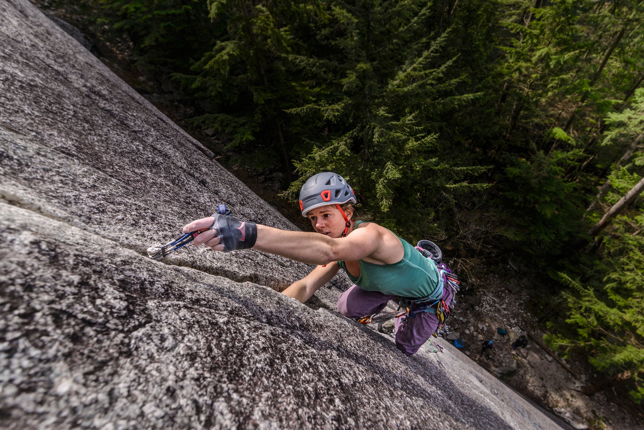 View from above of single adventurous woman rock climbing up cliff, Squamish, British Columbia, Canada