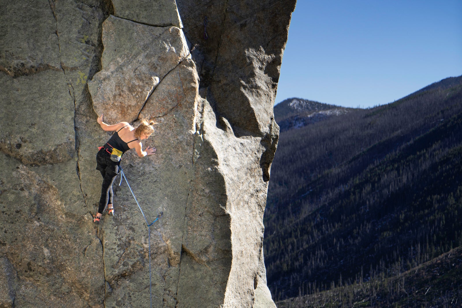 women rock climbing, looking down at belayer. she is practicing the gym to crag mistakes you need to avoid.