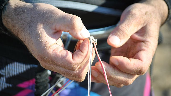 Rock climber tying know with parachute cord.