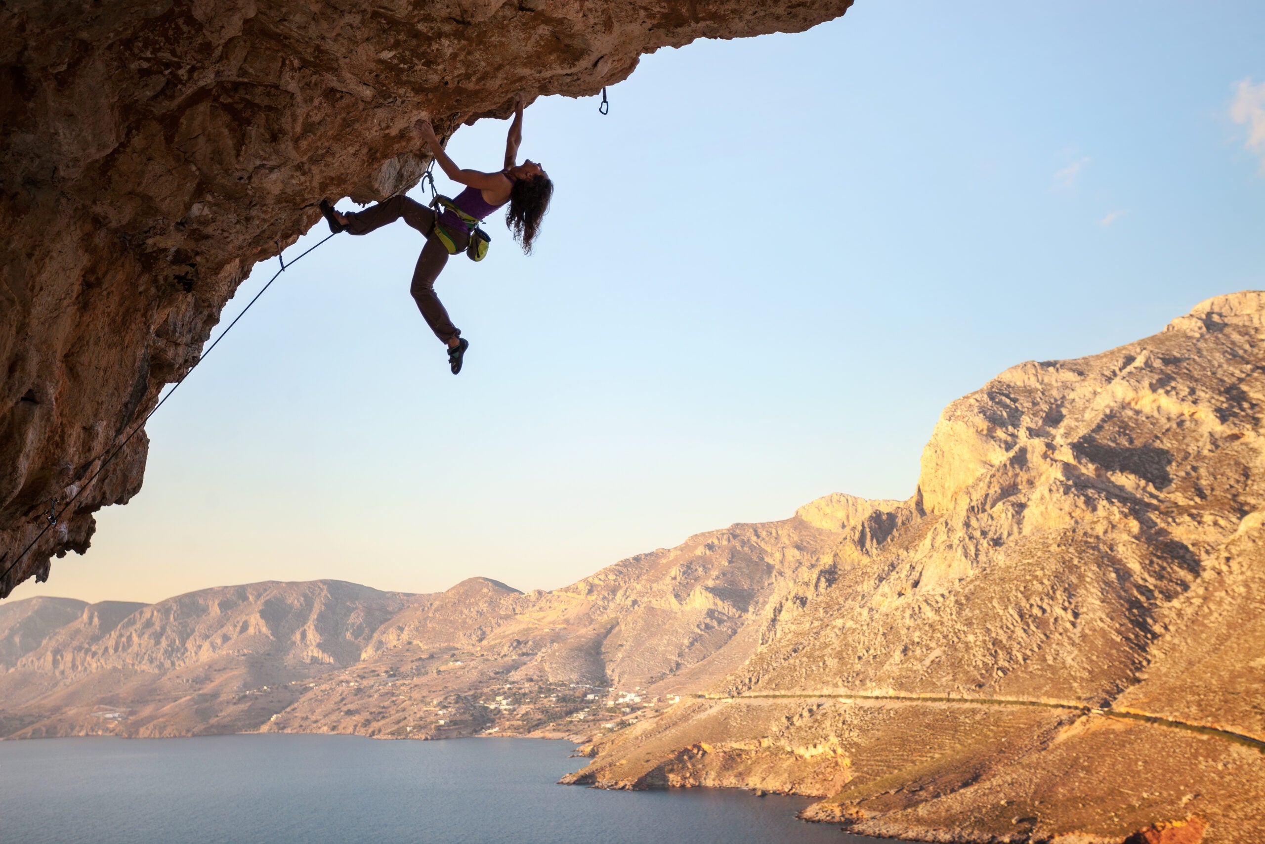 Silhouette of a young female rock climber on a cliff. Kalymnos Island, Greece