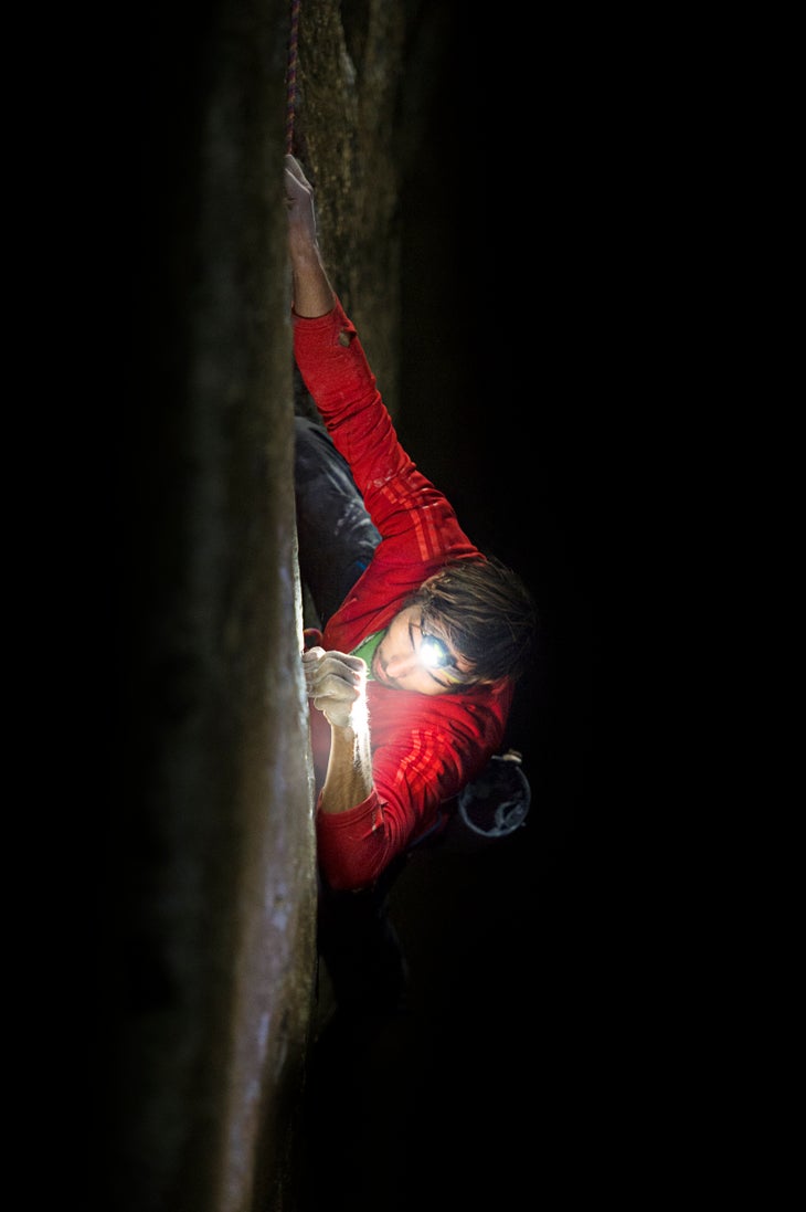 Action_Kevin Jorgeson climbing at night_(c)CoreyRich Close up shot from above of Kevin Jorgeson climbing at night by light of a headlamp. He's wearing a red mid-layer.