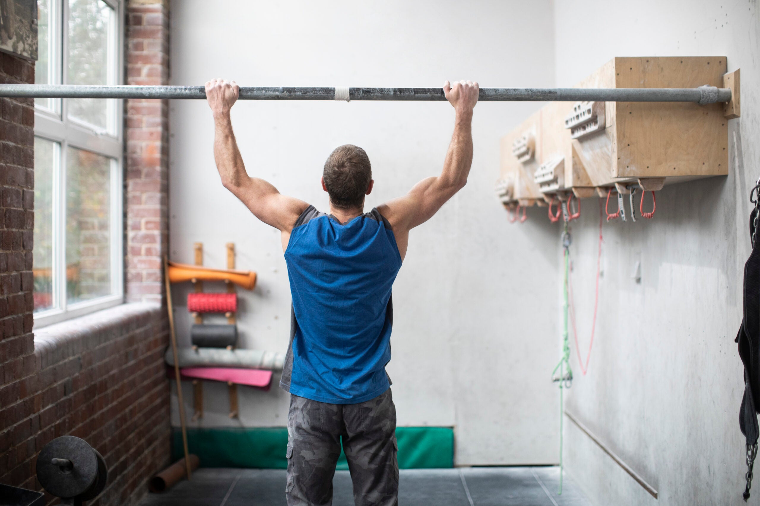 Rear view of man hanging on bar in gym