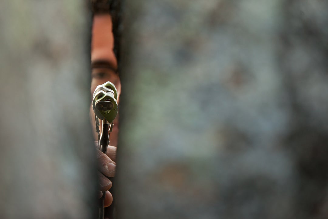 Climber places cam protection in rock.