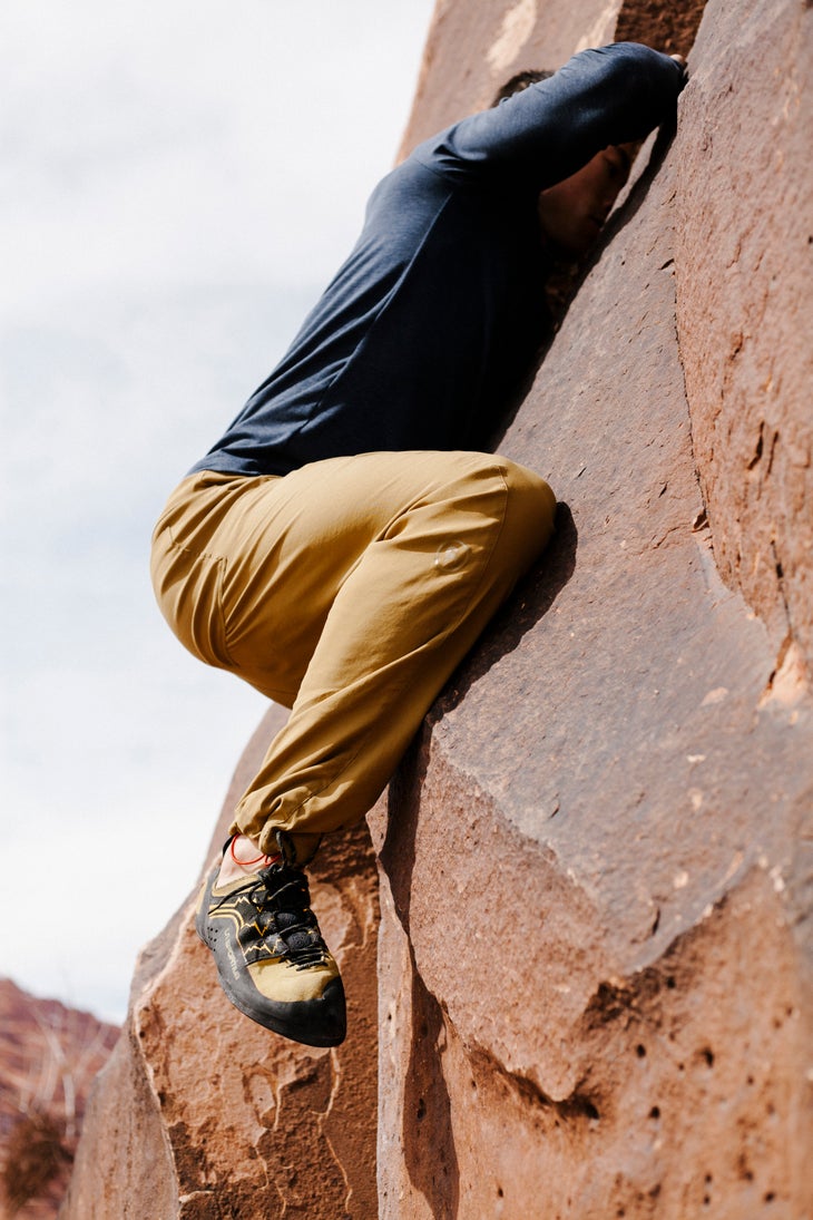 BCAndyB_190226_0098 Man in blue long sleeve shirt and beige pants clings to a red rock wall.