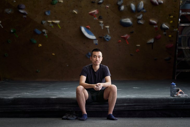 190228_KaiLin_NYC_Percival_09032 Kai Lin, a Chinese man, sits on the edge of a crash pad at a climbing gym.