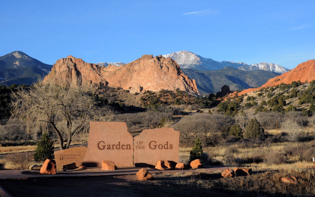 A sign marks the entrance to the Garden of the Gods park in Colorado Springs, Colorado. The National Natural Landmark features imposing red sandstone rock formations created during a geological upheaval millions of years ago. Snow-covered Pike's Peak is in the background. (Photo by Robert Alexander/Getty Images)