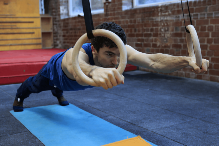 A climber trains by doing a plank on rings