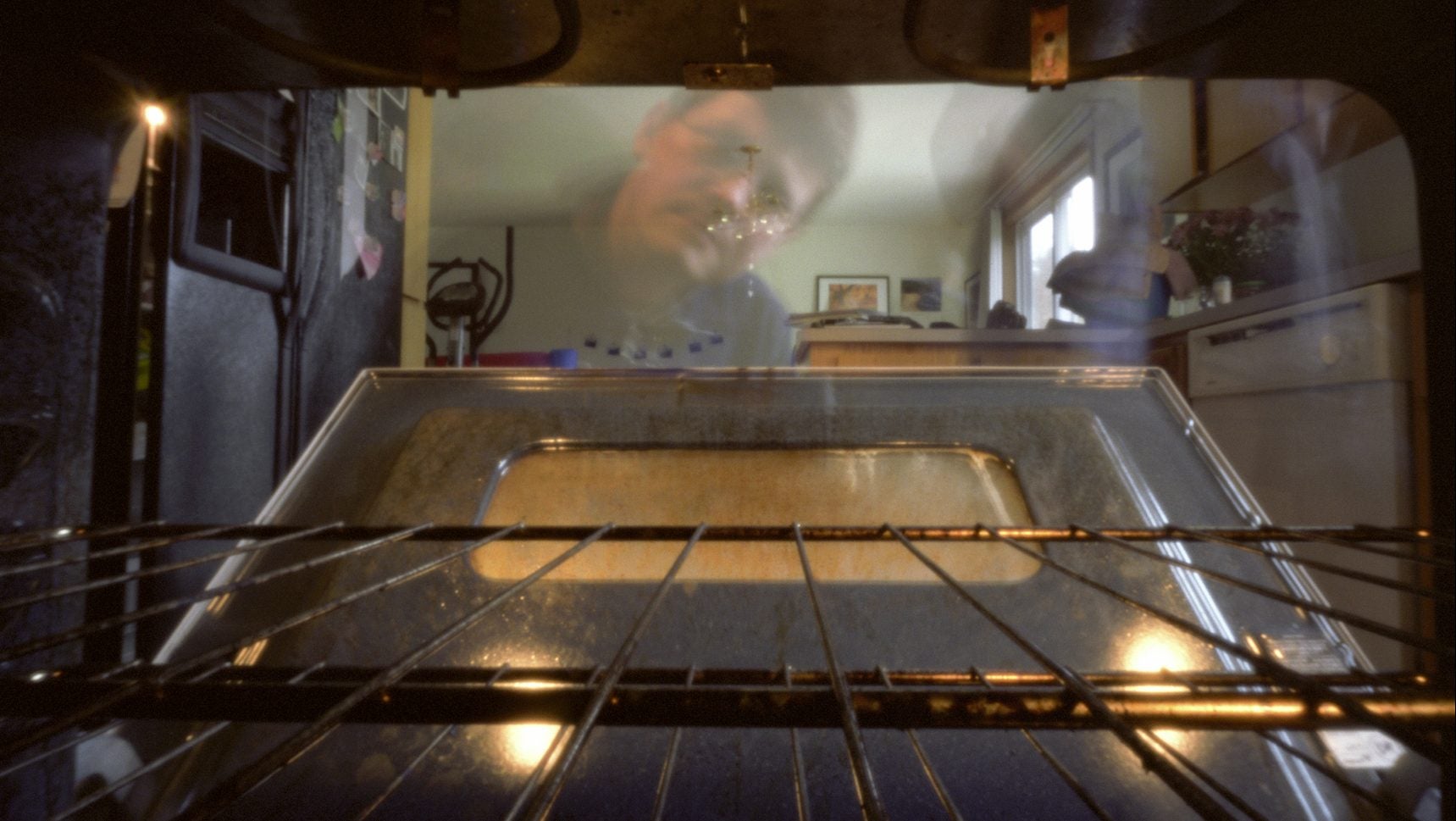 A pinhole image of a person peering into their oven at home.