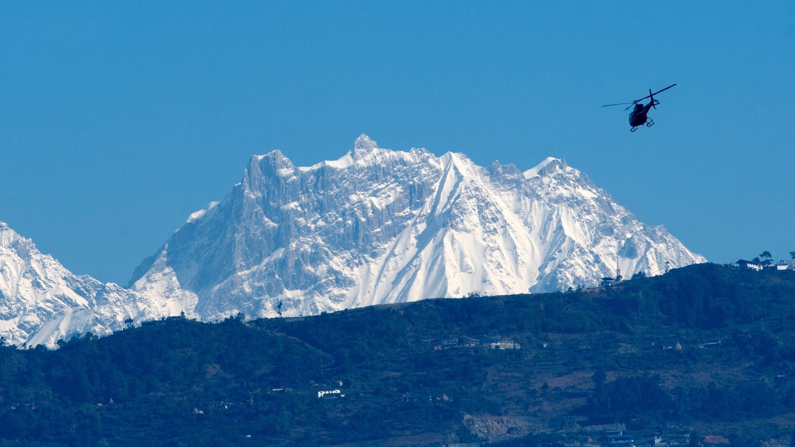 A helicopter flies with rescue team in front of the Annapurna mountain range, in Pokhara, some 200 km west of Kathmandu on January 22, 2020.