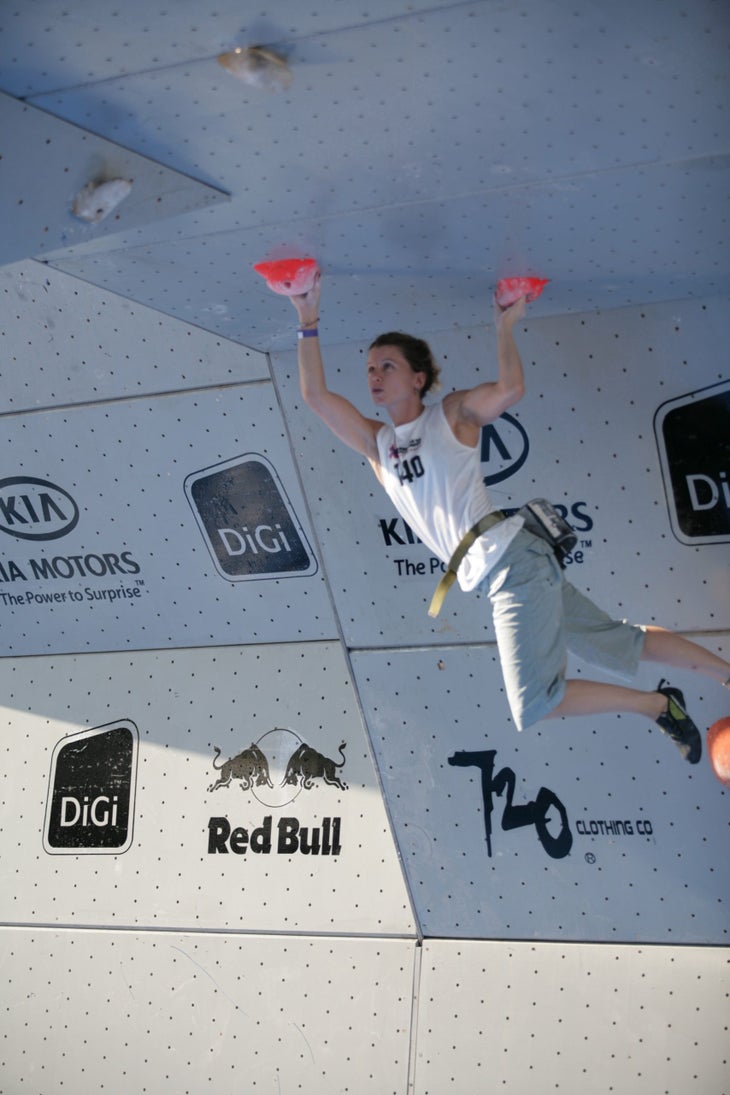 Climbing Chalk company founder Brandi Proffitt climbs in the X games, hanging from two red holds.