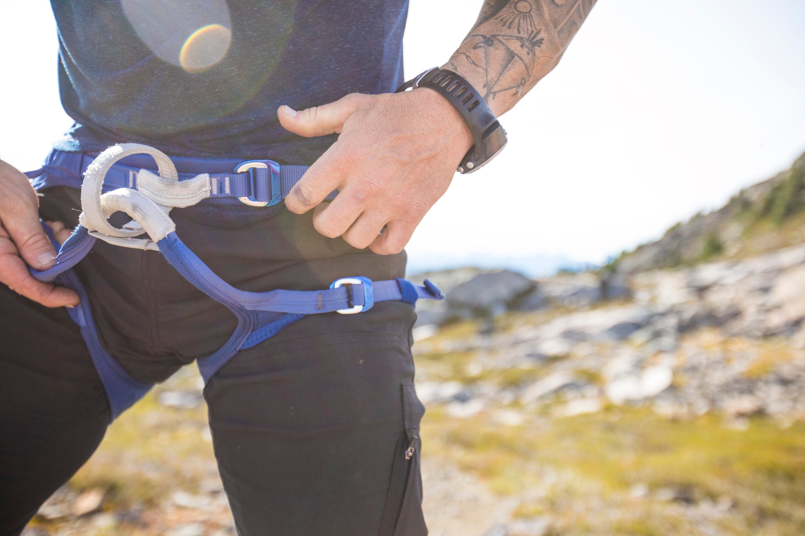 A climber checks his harness prior to beginning a rock climbing route
