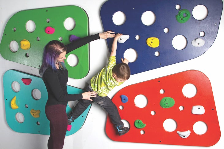 Toddler learns to rock climb under parent supervision