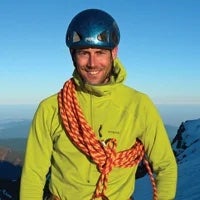 Man climbs in the mountains with a helmet.