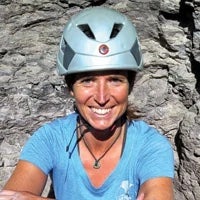 Woman climbs with a helmet.