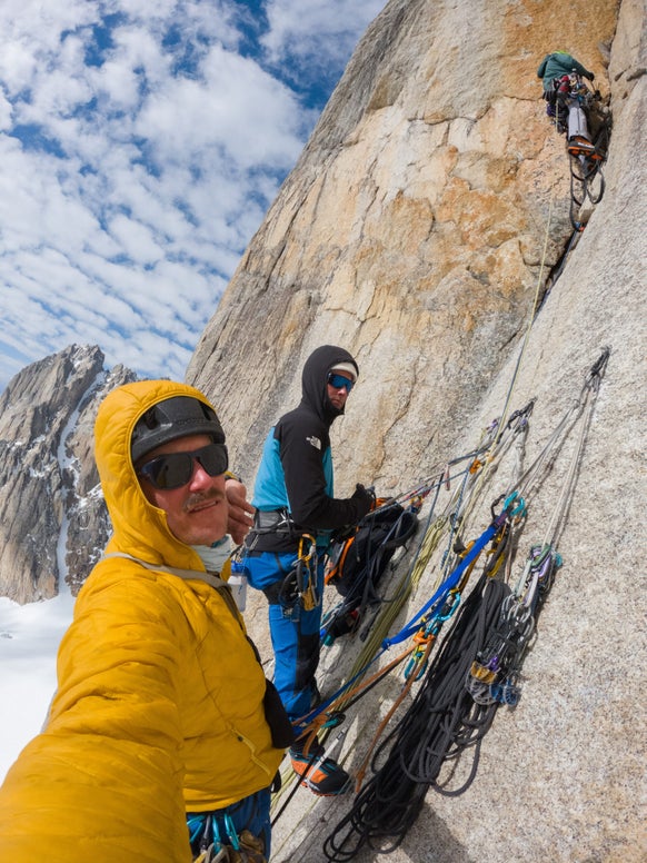 Three climbers ascend remote Alaskan mountain.