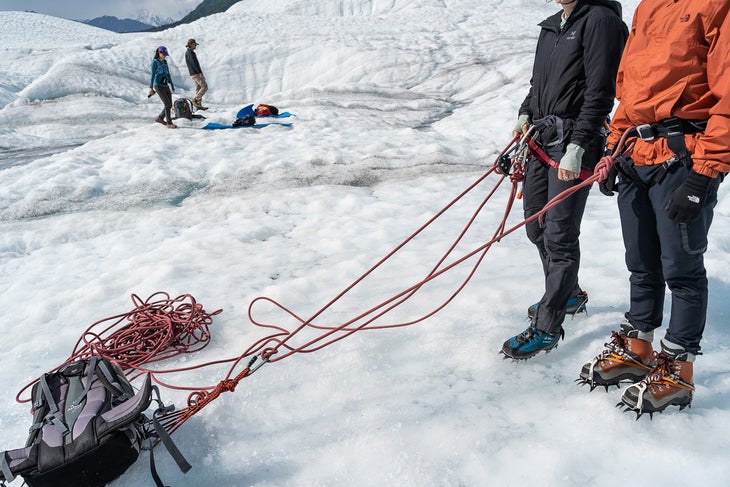 Two climbers prepare to descend into a glacier.