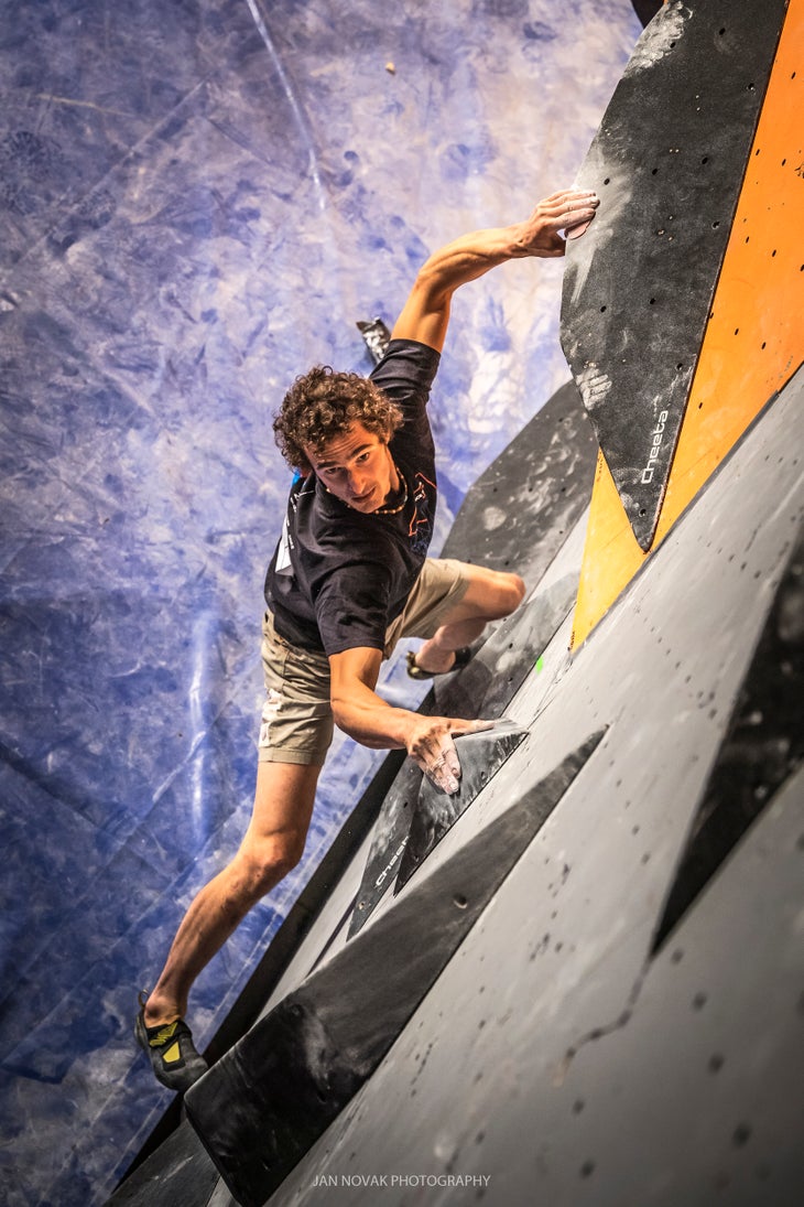 Adam Ondra holds a sloping hold during a climbing competition.