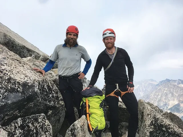 Two climbers stand on the summit of mountain in British Columbia.