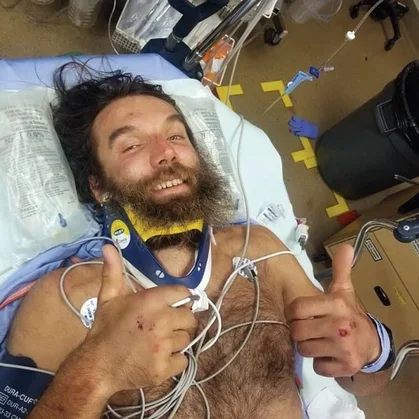 Climber poses in hospital bed after accident.