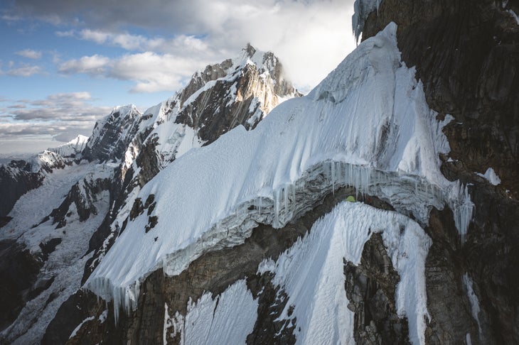 A tent on a mountainside under a roof of ice.