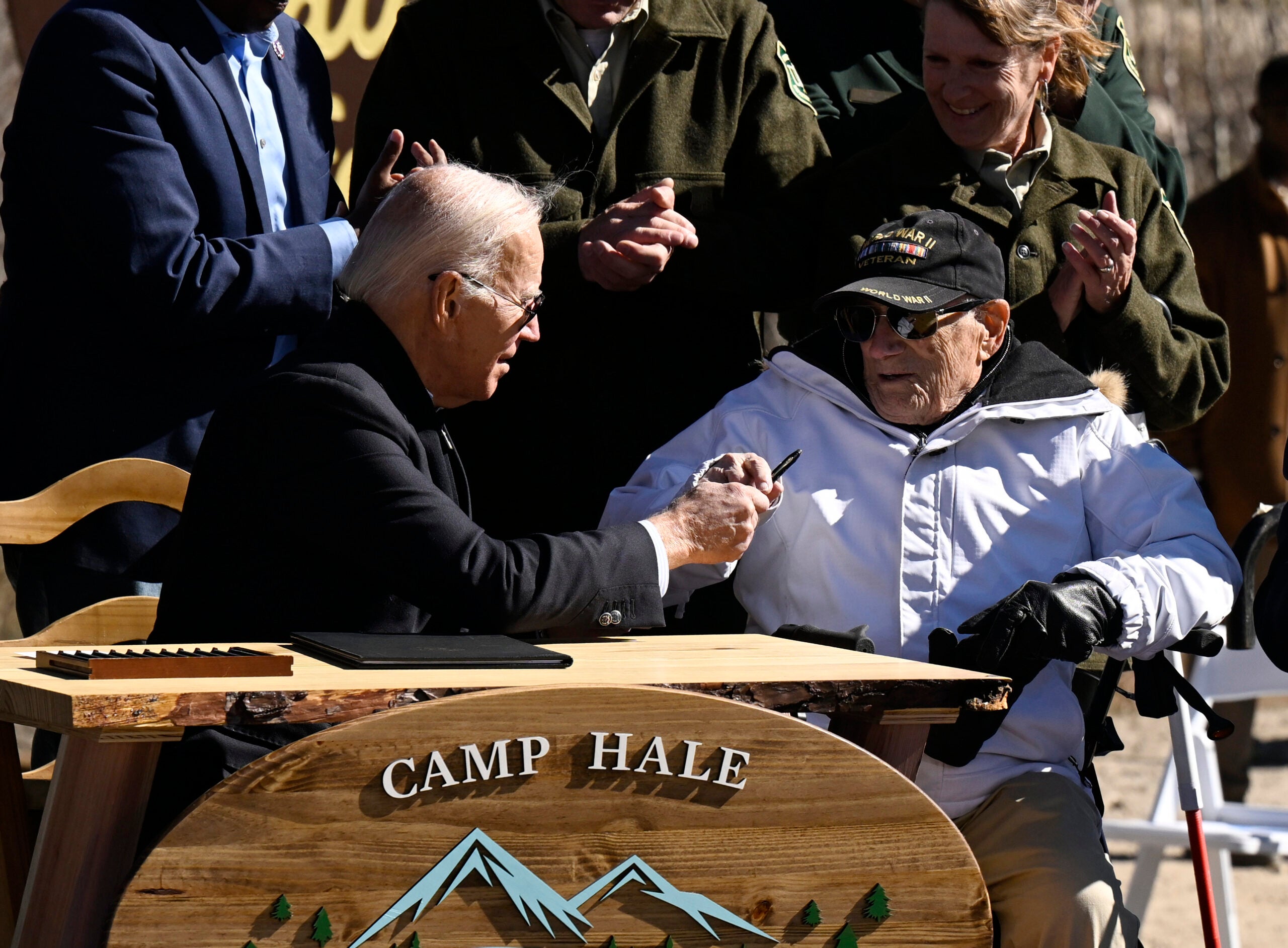 President Joe Biden hands a pen to World War II veteran Francis Bud Lovett, who was part of the 10th Mountain Division after signing a proclamation to designating Camp Hale, a World War II training ground, a new national monument. The US Army's 10th Mountain Division trained at Camp Hale in winter conditions similar to the conditions they fought in during WWII in the Italian Alps.
