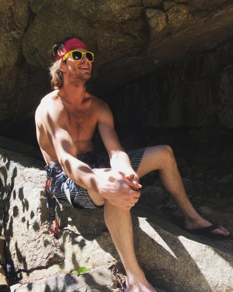 Squamish soloist Nathan Roberts smiles sitting on boulder in the sun.