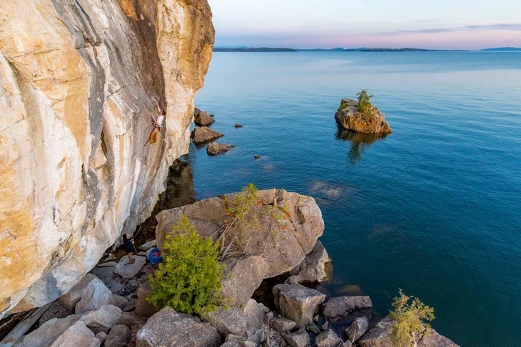 A climber climbing a sunset at Lone Rock Point in Burlington Vermont