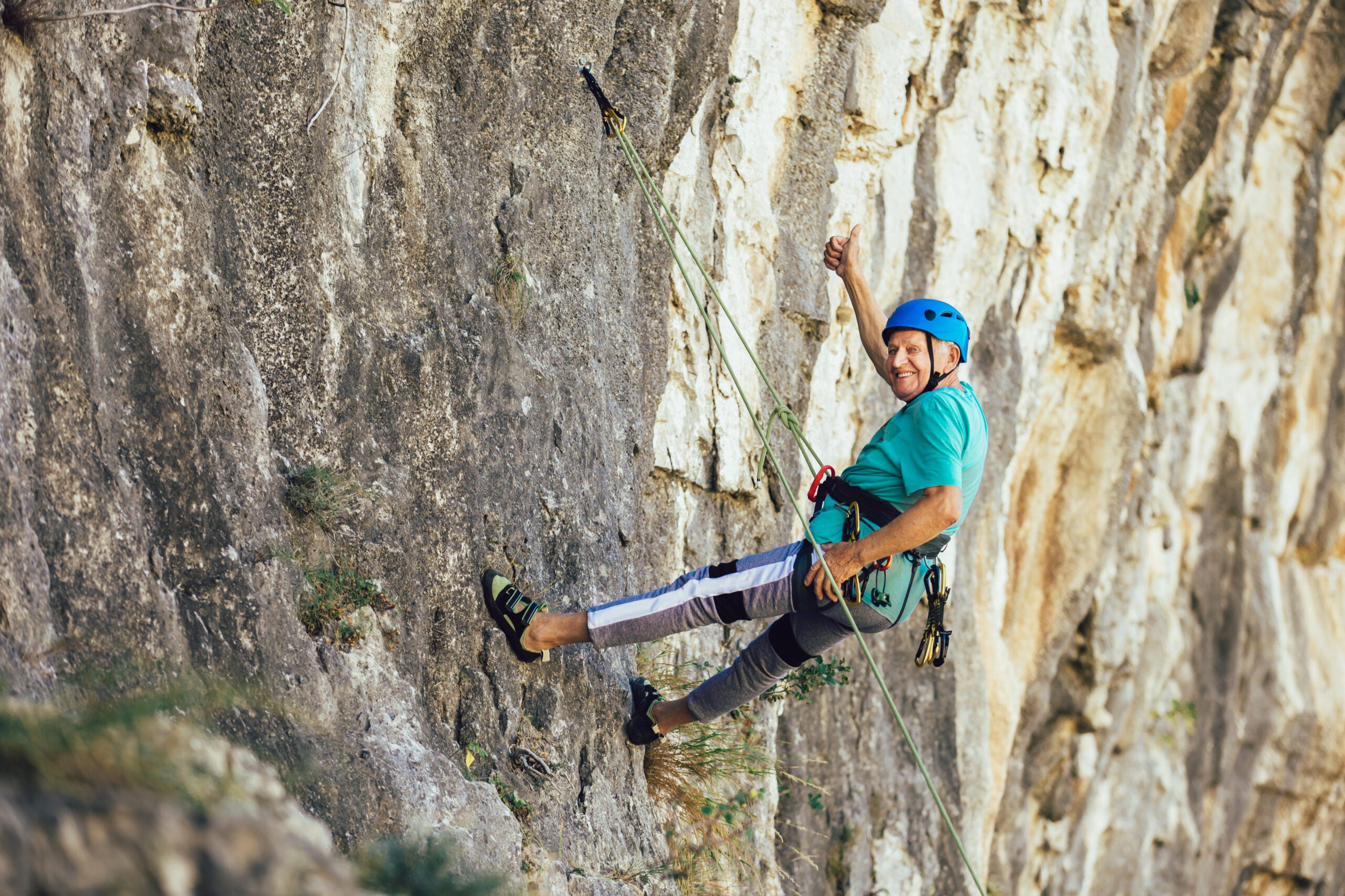 Senior man with a rope climbing on the rock.