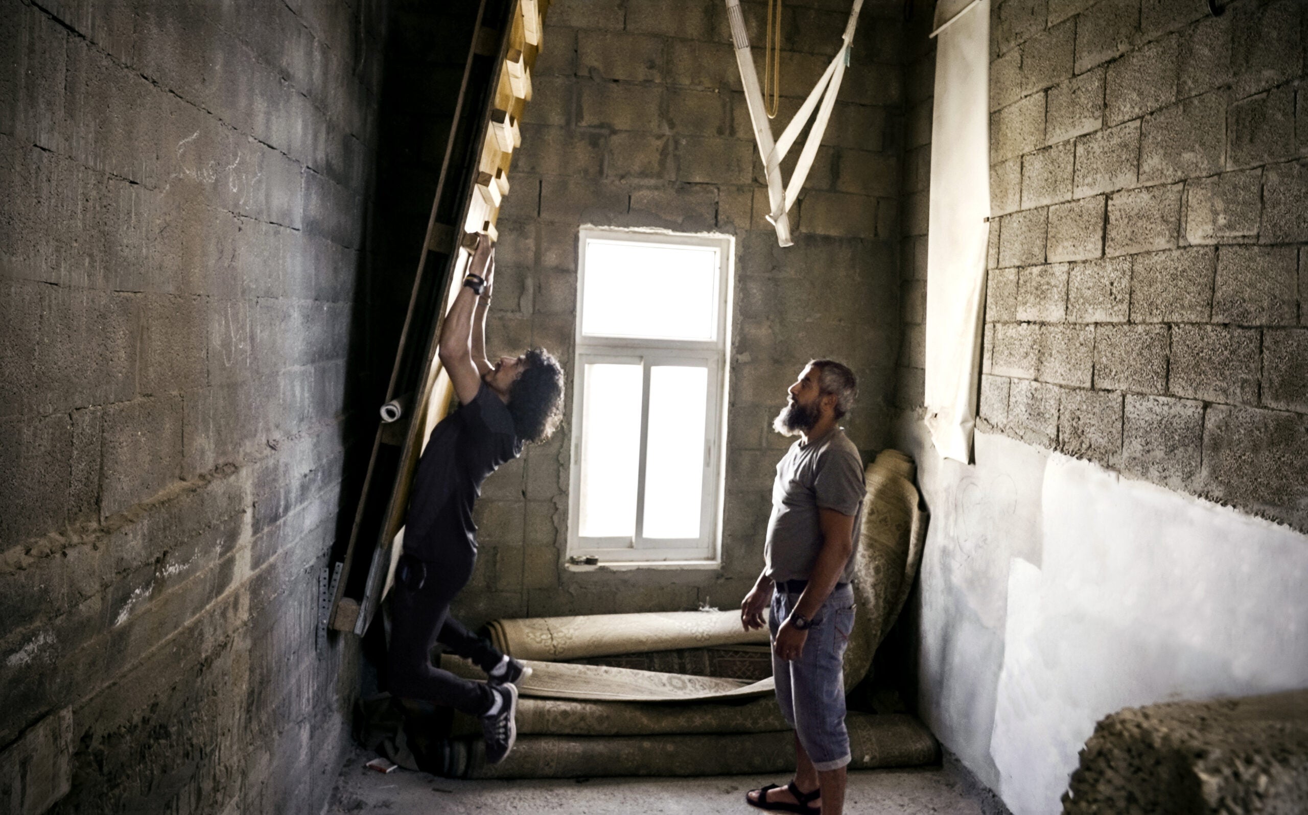 two Palestinian climbers using a campus board