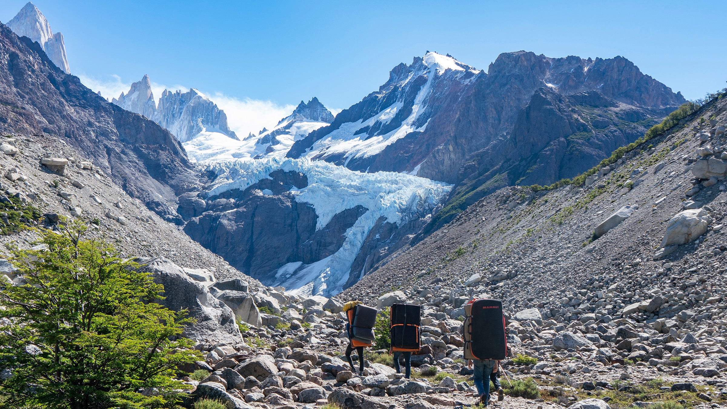 Climbers hiking in Patagonia mountain scape with crash pads on backs