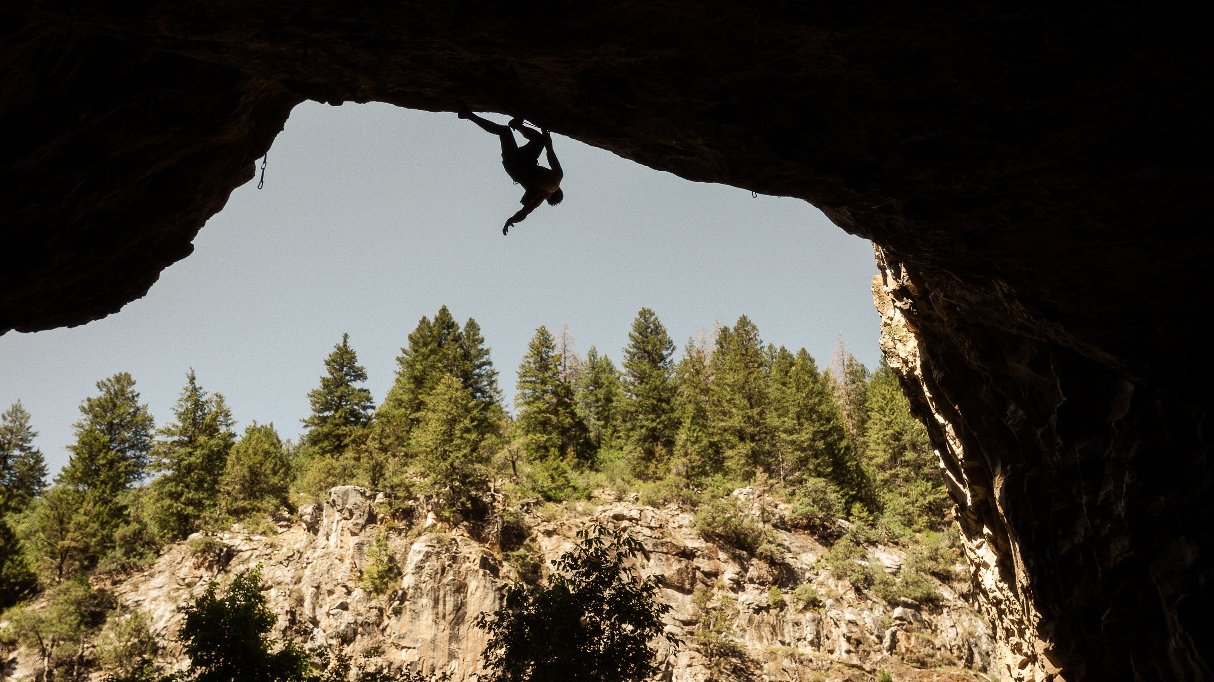 Man climbs overhanging rock at Rifle, CO's, Skull Cave.