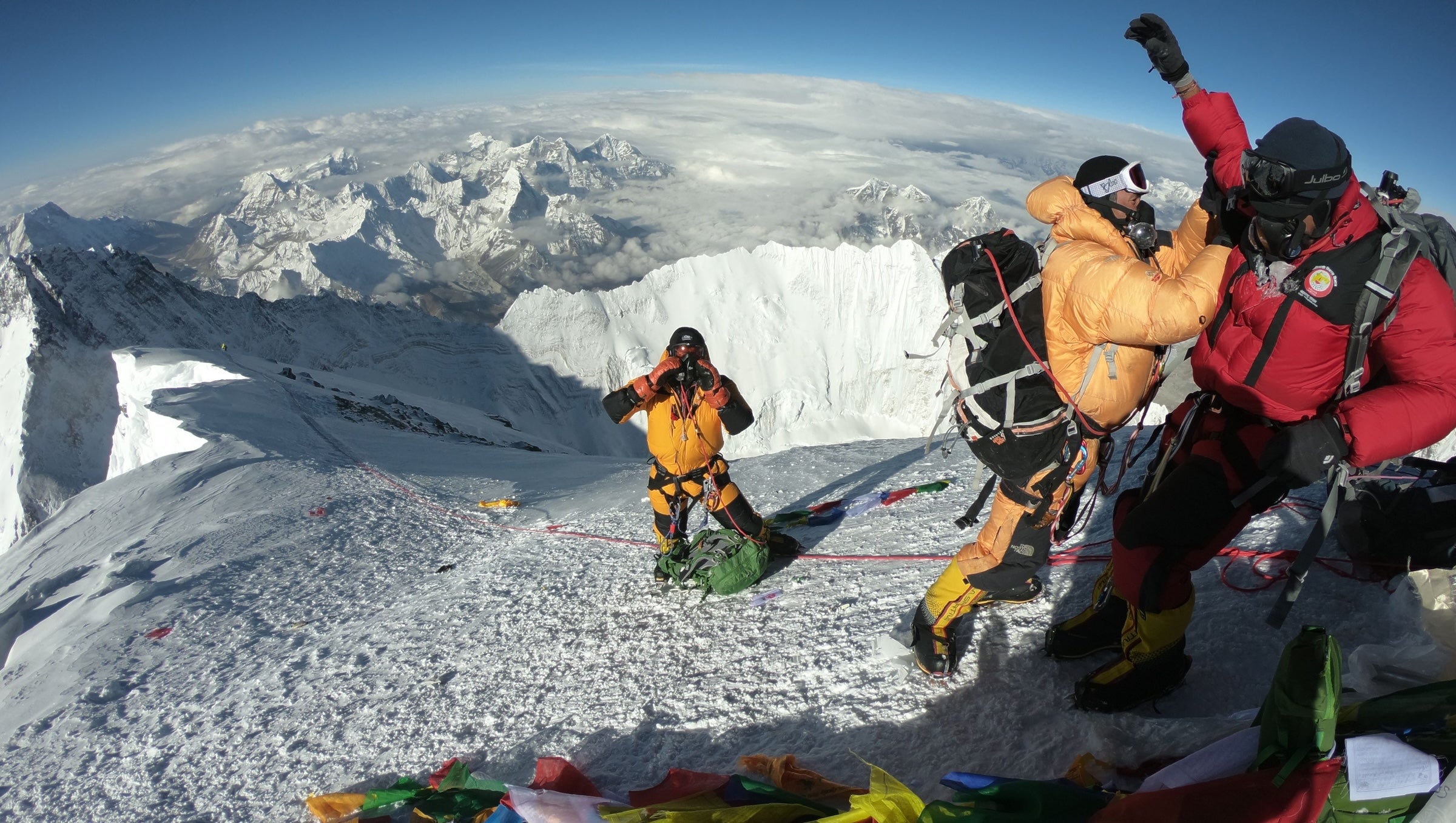 how much does it cost to climb Everest in 2026: a group of three climbers stand at the summit of Everest.